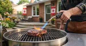 A chef using a propane torch lighter for grilling to quickly sear a thick ribeye steak on an outdoor barbecue grate.