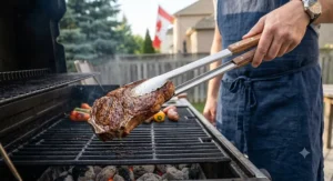 Close-up of long-handled stainless steel grill tongs lifting a thick steak off barbecue grates.